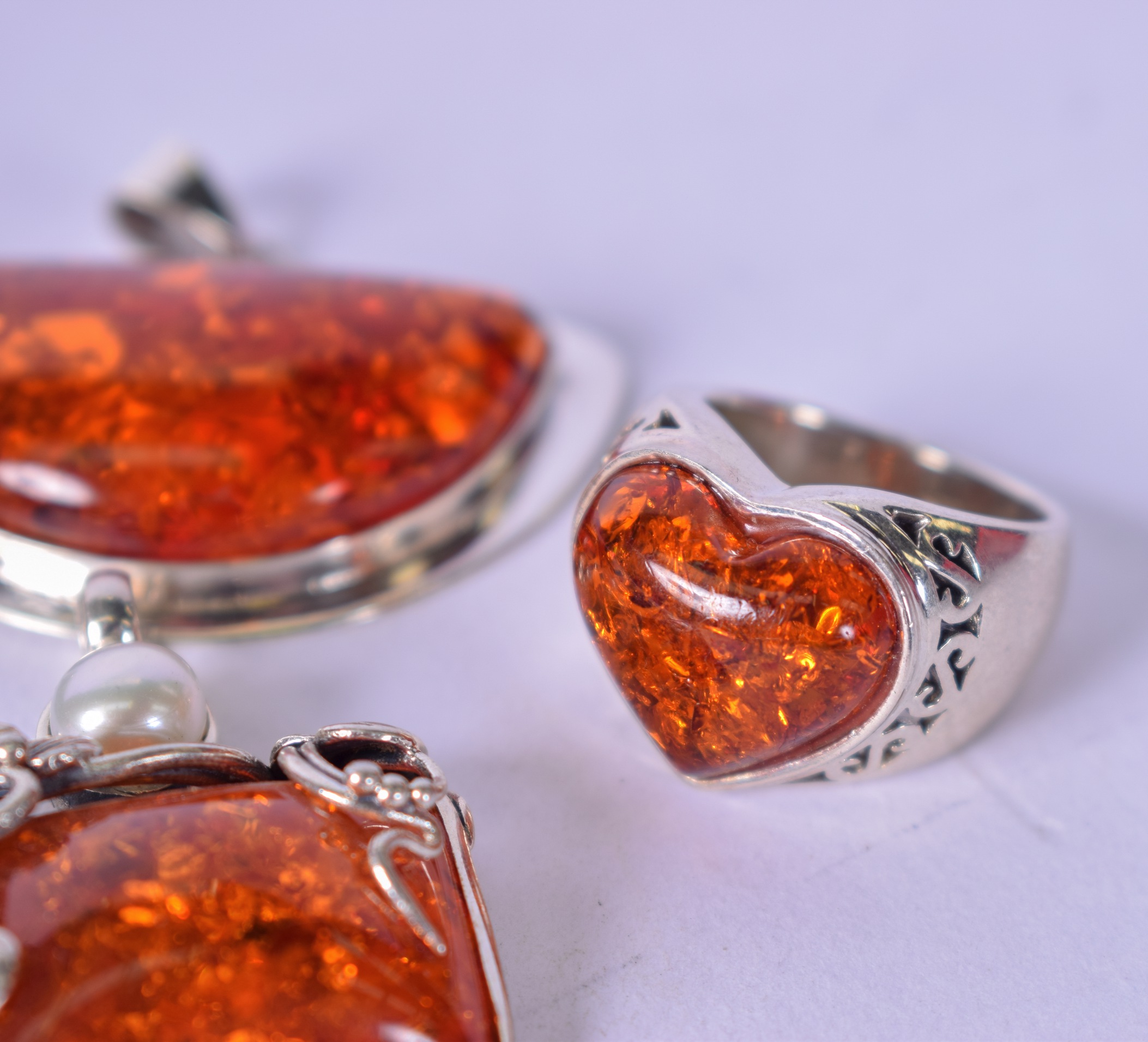 AN AMBER TYPE HEART SHAPED RING, together with three silver mounted pendants. (4) - Image 2 of 3