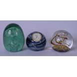 A VICTORIAN GREEN GLASS PAPERWEIGHT, together with a Caithness clock paperweight and another.