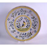 AN 18TH CENTURY CONTINENTAL FAIENCE TIN GLAZED DISH painted with a bird roaming amongst foliage.