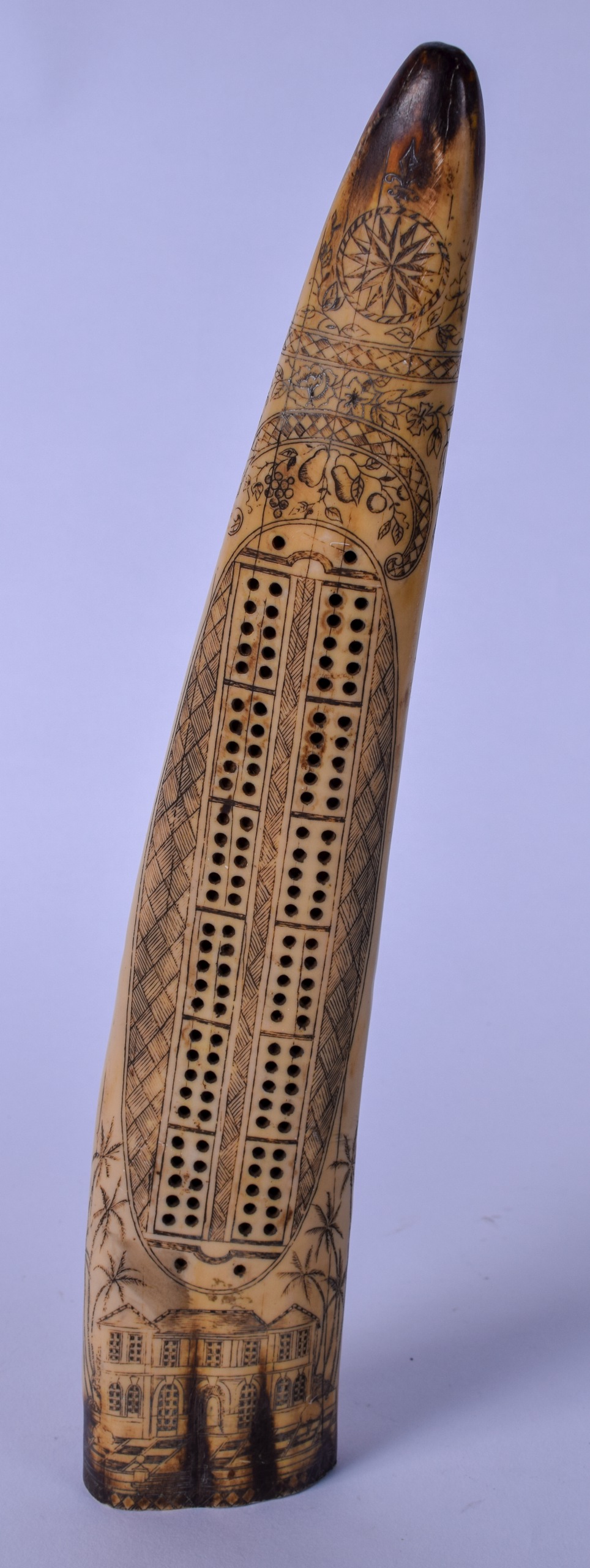 AN IVORINE SCRIMSHAW CRIBBAGE BOARD, decorated with a grand house and palm trees. 32 cm high.