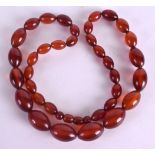 AN EARLY 20TH CENTURY CARVED AMBER NECKLACE. 54 cm long overall, largest bead 2.25 cm wide.