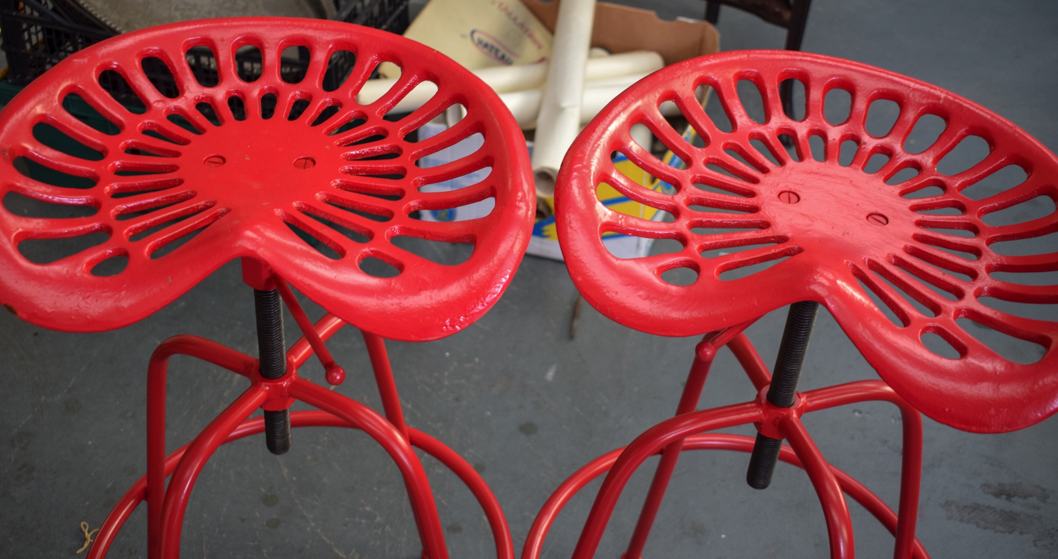 A STYLISH PAIR OF TRACTOR SEAT STOOLS, painted red. 84 cm high. - Image 2 of 2