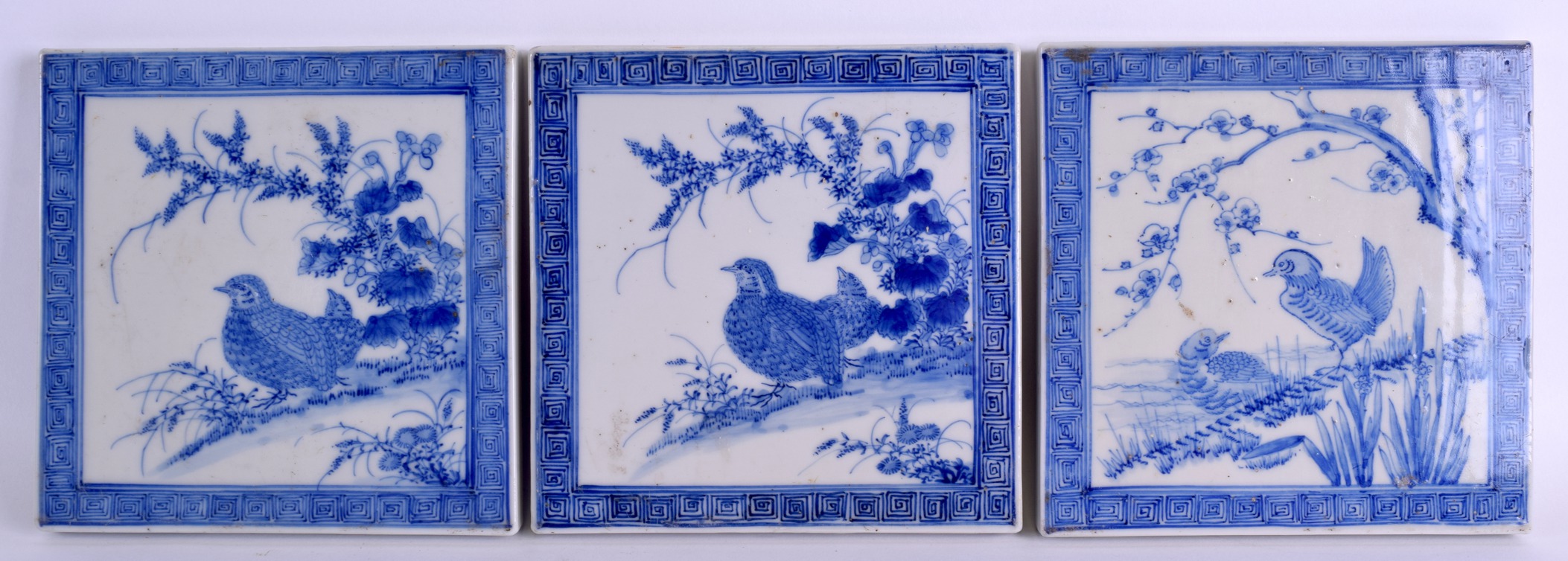 A SET OF THREE 19TH CENTURY JAPANESE BLUE AND WHITE TILES painted with game birds within landscapes.