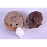 AN EARLY ETRUSCAN TERRACOTTA WHEEL SHAPED TABLET together with an early stone head. (2)