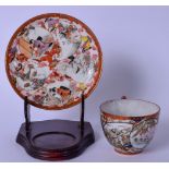 A JAPANESE MEIJI PERIOD KUTANI PORCELAIN TEA CUP AND SAUCER, painted with figures in panels and