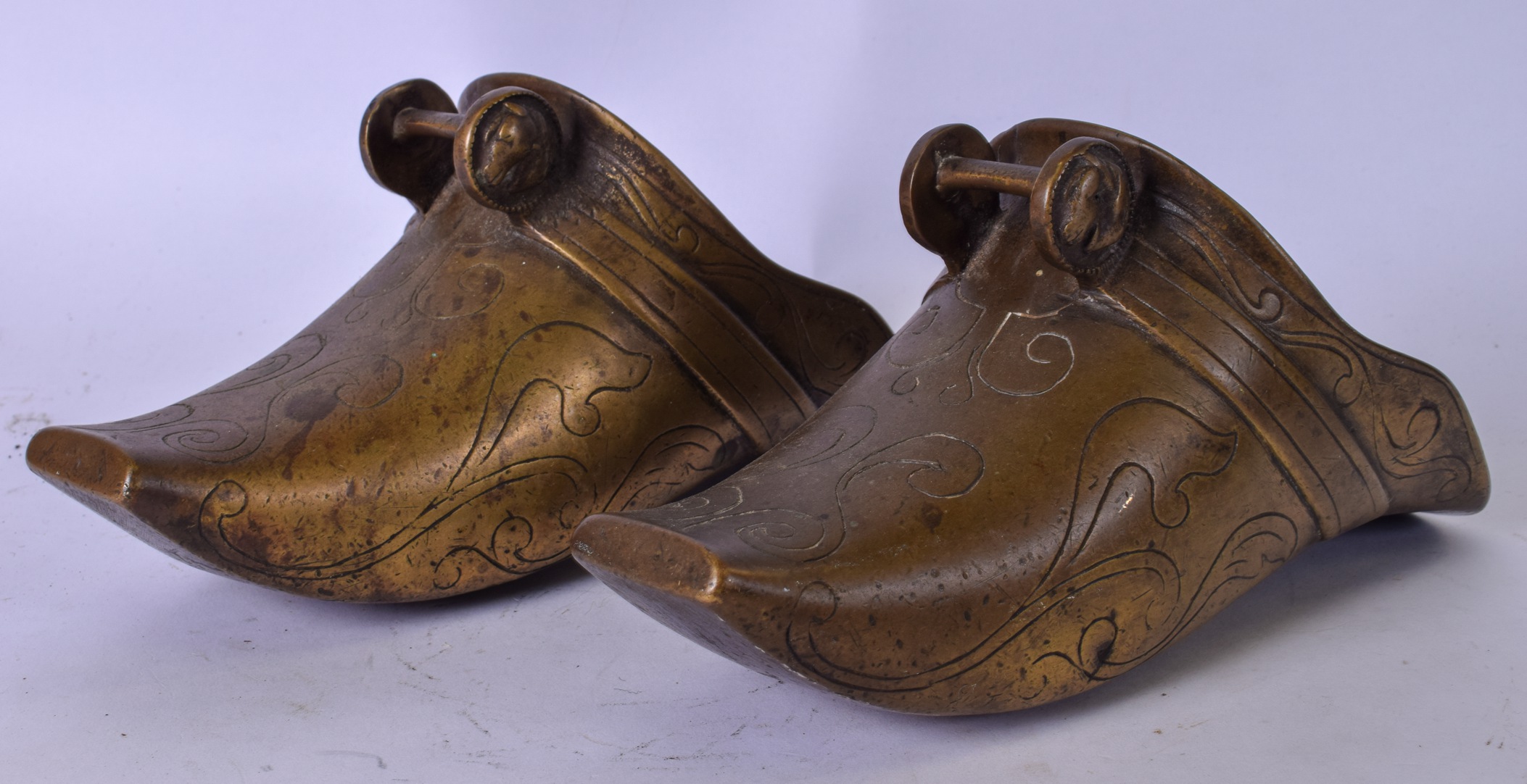 A LARGE PAIR OF EASTERN BRONZE SHOES, engraved with foliate inspired design. 26 cm long.