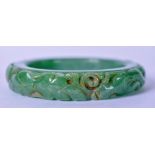 A CHINESE GREEN JADEITE BANGLE, carved with a swimming fish. 7.5 cm (inner diameter 5.5 cm)