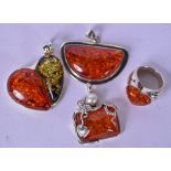 AN AMBER TYPE HEART SHAPED RING, together with three silver mounted pendants. (4)