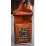 AN EARLY 20TH CENTURY OAK HANGING CORNER CABINET, the door inset with a stained glass panel. 115