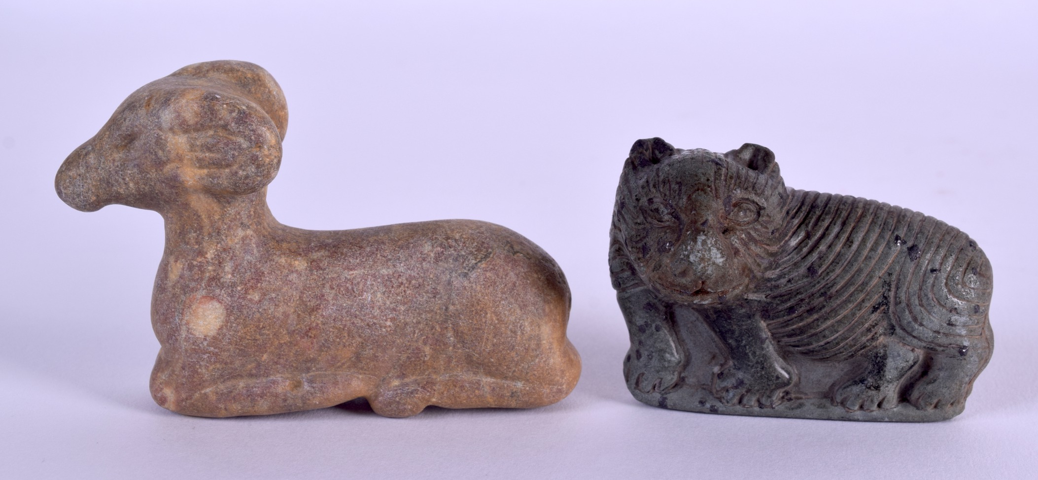 A 19TH CENTURY CENTRAL ASIAN CARVED STONE RECUMBANT DEER together with an early carved stone lion. 8