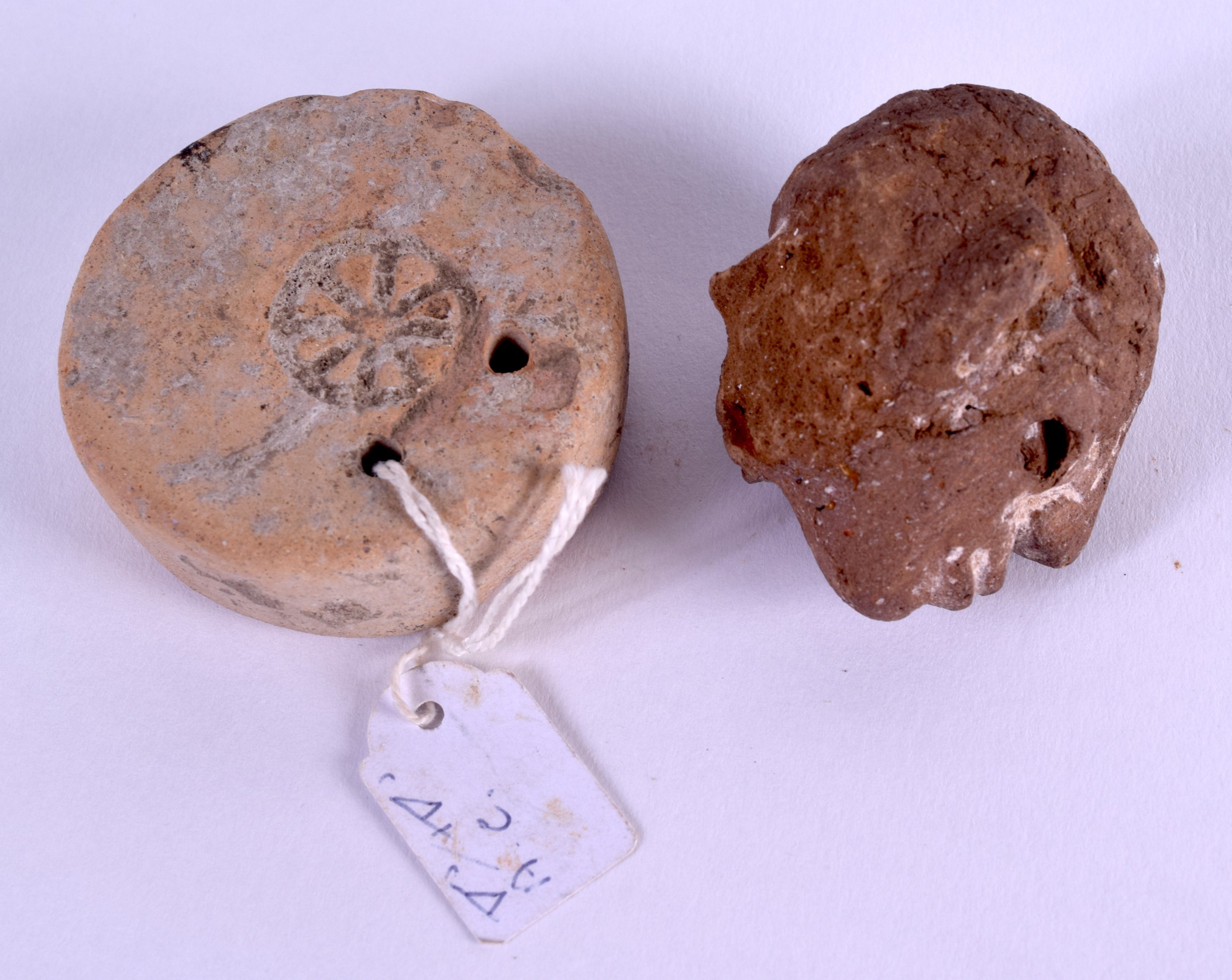 AN EARLY ETRUSCAN TERRACOTTA WHEEL SHAPED TABLET together with an early stone head. (2) - Image 2 of 2