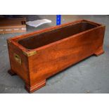 AN UNSUAL EARLY 20TH CENTURY CARVED WOODEN CAMPAIGN PLANTER, formed with heavy brass handles. 23