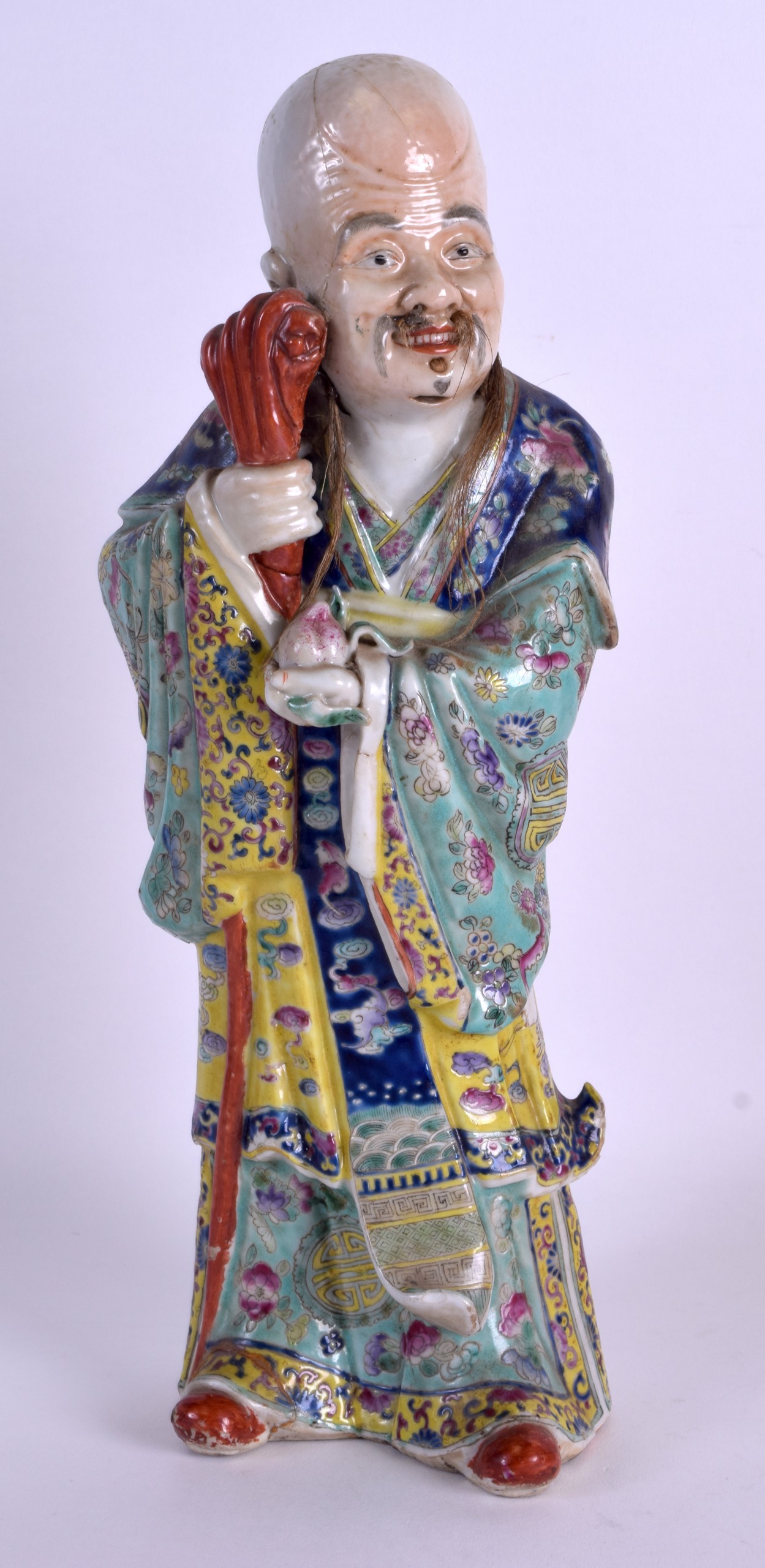 A 19TH CENTURY CHINESE FAMILLE ROSE PORCELAIN FIGURE OF AN IMMORTAL modelled holding a peach and