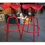 A STYLISH PAIR OF TRACTOR SEAT STOOLS, painted red. 84 cm high.