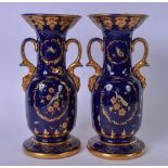 A PAIR OF BLUE GROUND TWIN HANDLED PORCELAIN VASES, decorated with birds amongst foliage. 26 cm