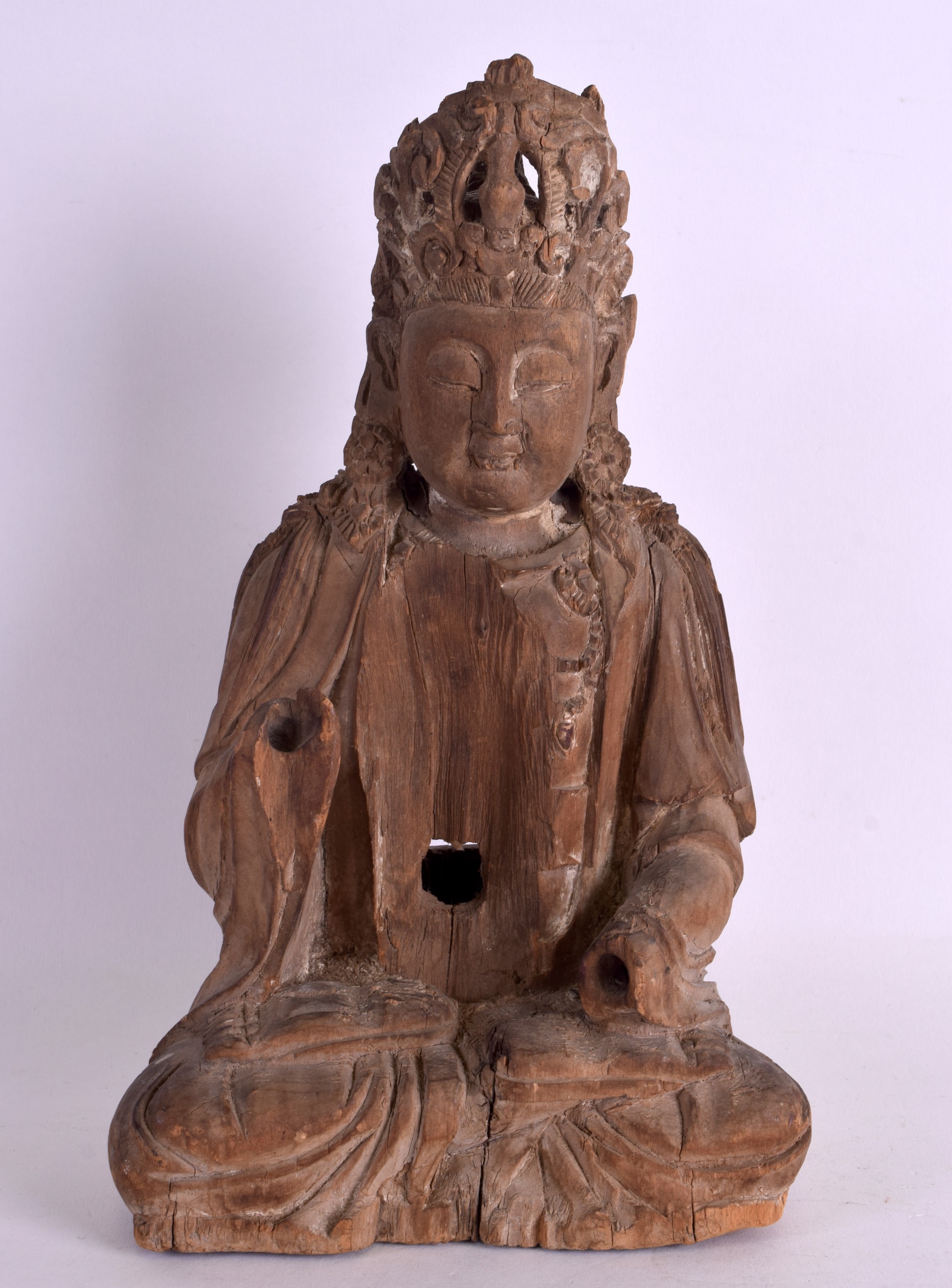 A CHINESE YUAN/MING DYNASTY CARVED WOOD FIGURE OF A SEATED BUDDHA elegantly modelled with an arm