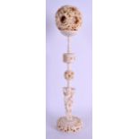 A 19TH CENTURY CHINESE CANTON CARVED IVORY PUZZLE BALL ON STAND formed as a standing figure