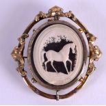 A MID 19TH CENTURY YELLOW METAL AND IVORY BROOCH decorated with a horse within a landscape. 6 cm x