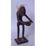 A 19TH/20TH CENTURY WOODEN TRIBAL FIGURE, modelled standing with a drum by his side. 21 cm high.