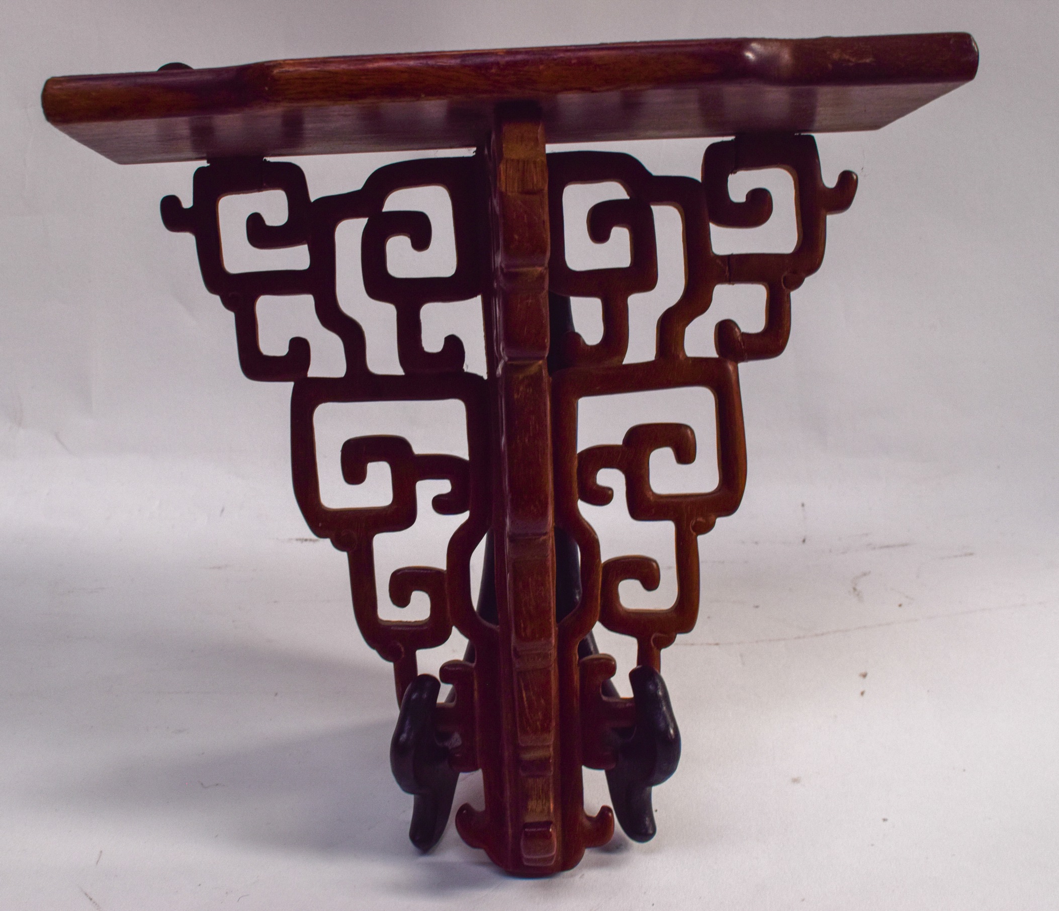 AN EARLY 20TH CENTURY CHINESE CARVED HARDWOOD DISPLAY SHELF OR BRACKET, formed with Greek key type