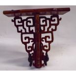 AN EARLY 20TH CENTURY CHINESE CARVED HARDWOOD DISPLAY SHELF OR BRACKET, formed with Greek key type