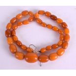 AN EARLY 20TH CENTURY CARVED HONEY AMBER NECKLACE. 23 grams. Largest bead 2 cm wide, 44 cm long.
