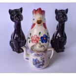 A PAIR OF BLACK CAT PORCELAIN CANDLESTICK HOLDERS, together with a ceramic chicken and a tea pot.