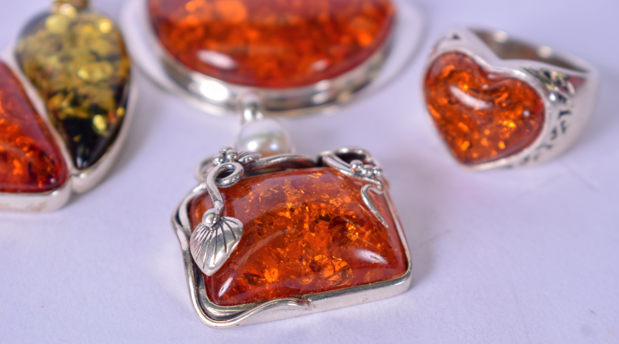 AN AMBER TYPE HEART SHAPED RING, together with three silver mounted pendants. (4) - Image 3 of 3