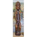 A LARGE AFRICAN TRIBAL WOODEN STATUE OF A FEMALE, formed standing with her hands clasped around