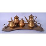AN EARLY 20TH CENTURY HAMMERED BRASS TEA SET, complete with tray and various tea pots etc. Tray 61