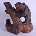 AN EARLY 20TH CENTURY BAVARIAN BLACK FOREST FIGURE OF A BEAR modelled resting upon a tree stump.