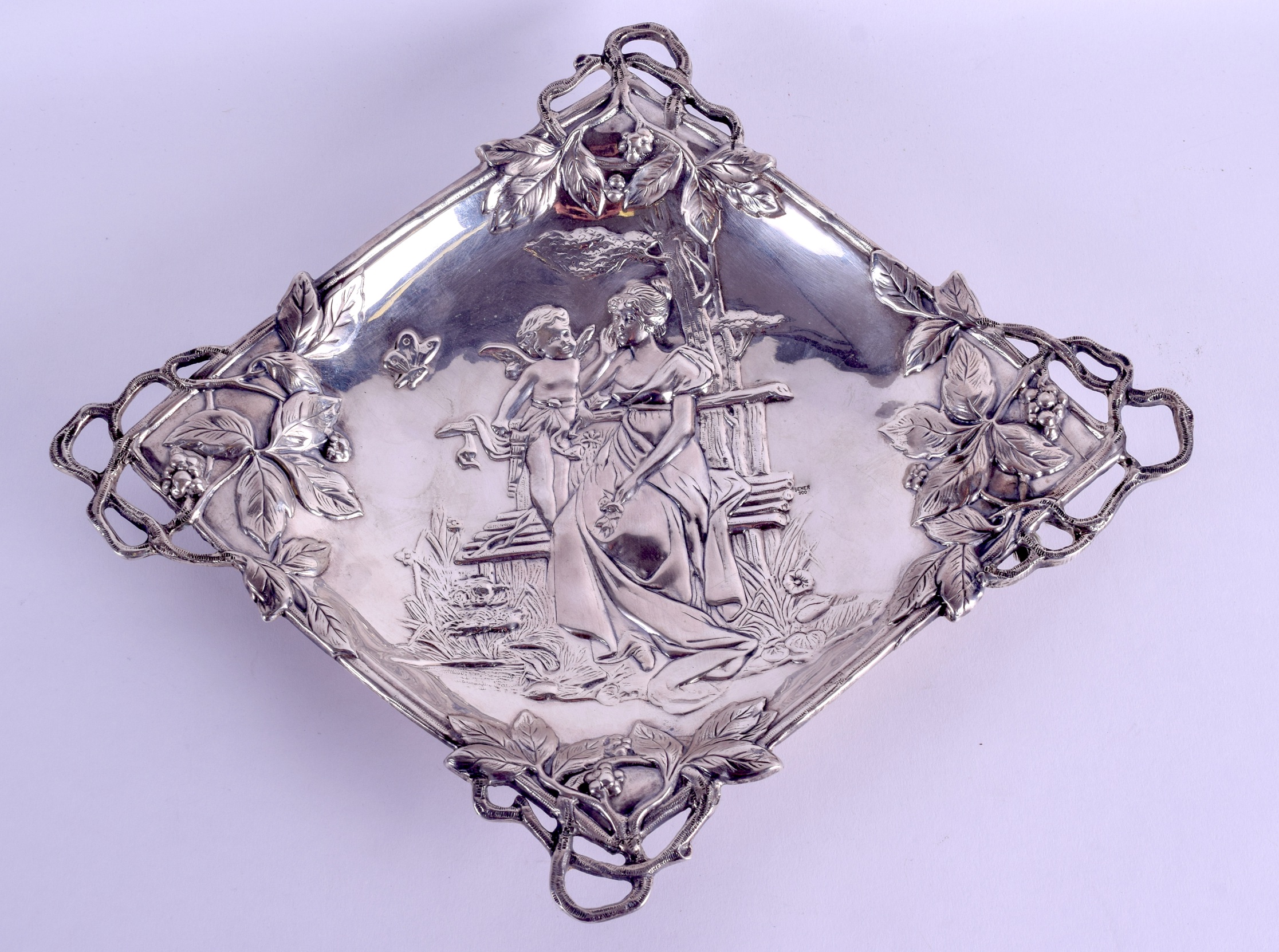 AN ART NOUVEAU CONTINENTAL SILVER LOZENGE SHAPED DISH decorated with figures seated upon a bench.