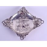 AN ART NOUVEAU CONTINENTAL SILVER LOZENGE SHAPED DISH decorated with figures seated upon a bench.