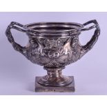 AN ENGLISH SILVER TWIN HANDLED WARWICK VASE decorated with classical figures upon a pedestal base.