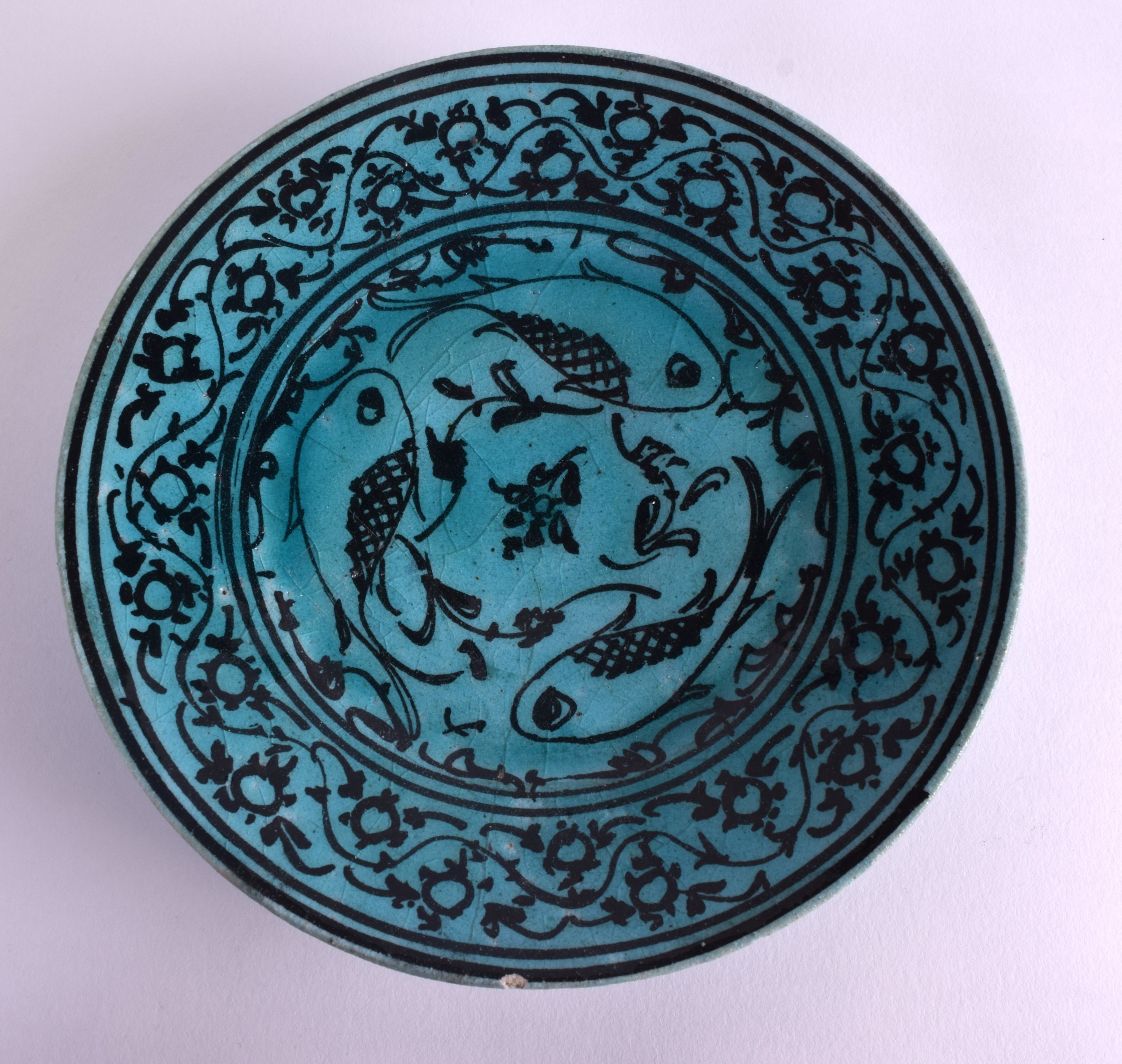 A PERSIAN BLUE GLAZED CIRCULAR POTTERY DISH painted with stylised fish and vines. 18 cm diameter.