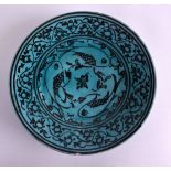 A PERSIAN BLUE GLAZED CIRCULAR POTTERY DISH painted with stylised fish and vines. 18 cm diameter.