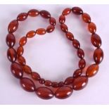 AN EARLY 20TH CENTURY CARVED AMBER NECKLACE. 54 cm long overall, largest bead 2.25 cm wide.Good