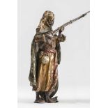 AN AUSTRIAN COLD PAINTED BRONZE by Franz Bergman, cast as an Arab standing wearing a gilt headdress,