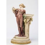 AN ART NOUVEAU ROYAL DUX BISQUE PORCELAIN FIGURAL VASE, modelled as a young lady wearing a dusky