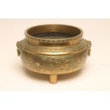 A CHINESE BRONZE CENSOR of cylindrical form with two mask ring handles raised upon three peg feet,