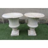 A PAIR OF VICTORIAN CAST IRON URNS of half fluted campana form with ovolu rims, and square base, 15"