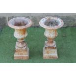A PAIR OF SMALL CAST IRON GARDEN URNS of fluted campana form with ovolu rim and square base,