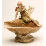 AN ART NOUVEAU ROYAL DUX BISQUE PORCELAIN FIGURAL CENTREPIECE, modelled as a young maiden wearing