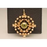 AN EDWARDIAN PERIDOT AND SEED PEARL PENDANT/BROOCH, the central round facet cut peridot open back
