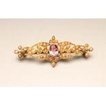 A LATE VICTORIAN 15CT GOLD BROOCH, centred by an oval facet cut pink tourmaline within a seed