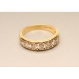 A SEVEN STONE DIAMOND RING, the graduated brilliant cut stones in a plain 18ct gold panel and shank,