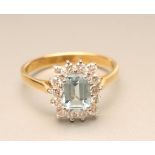 AN AQUAMARINE AND DIAMOND CLUSTER RING, the rectangular cut aquamarine claw set in a border of