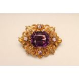 A VICTORIAN AMETHYST BROOCH, centred by an open back collet set oblong cut stone in a filigree mount