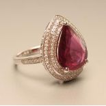 A RUBY AND DIAMOND CLUSTER RING, the pear cut ruby of approximately 6.25cts claw set to a double