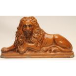 A VICTORIAN DERBYSHIRE FLATBACK STONEWARE FIREPLACE LION, the recumbent beast on a canted oblong